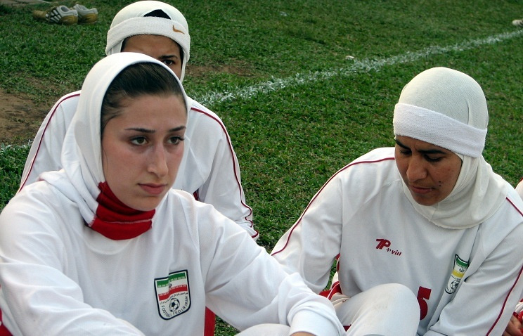 Iran's women's football team sitting on the pitch