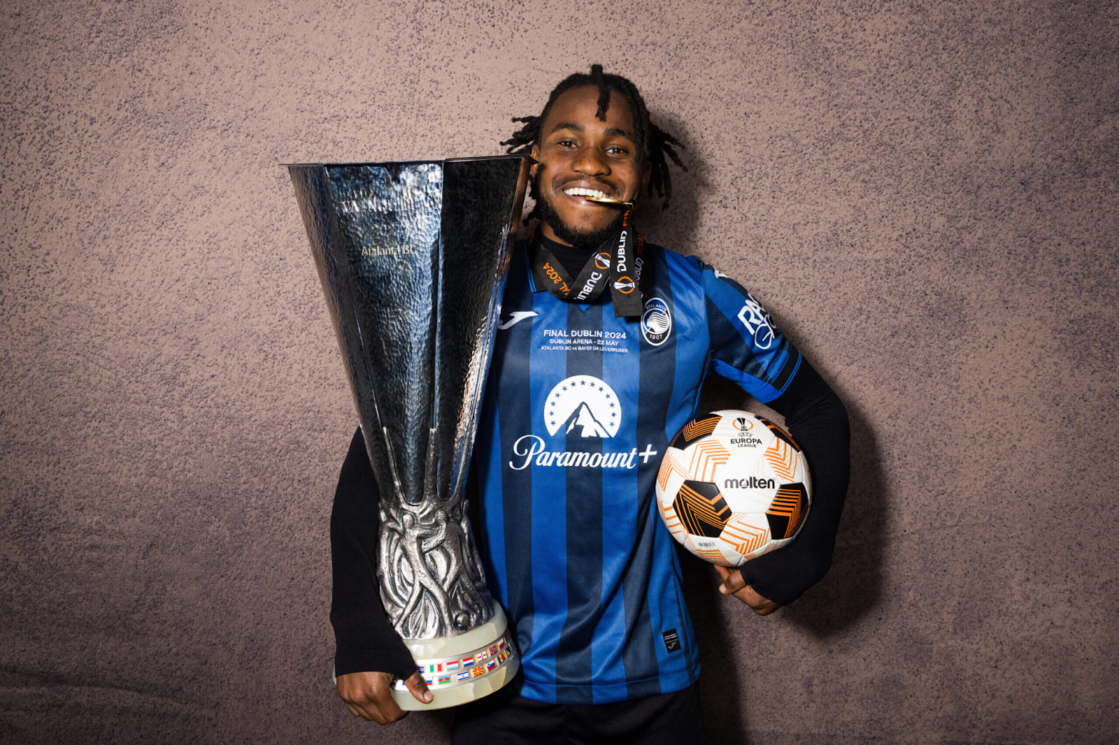Ademola Lookman celebrating with Europa League trophy, match ball, and medal