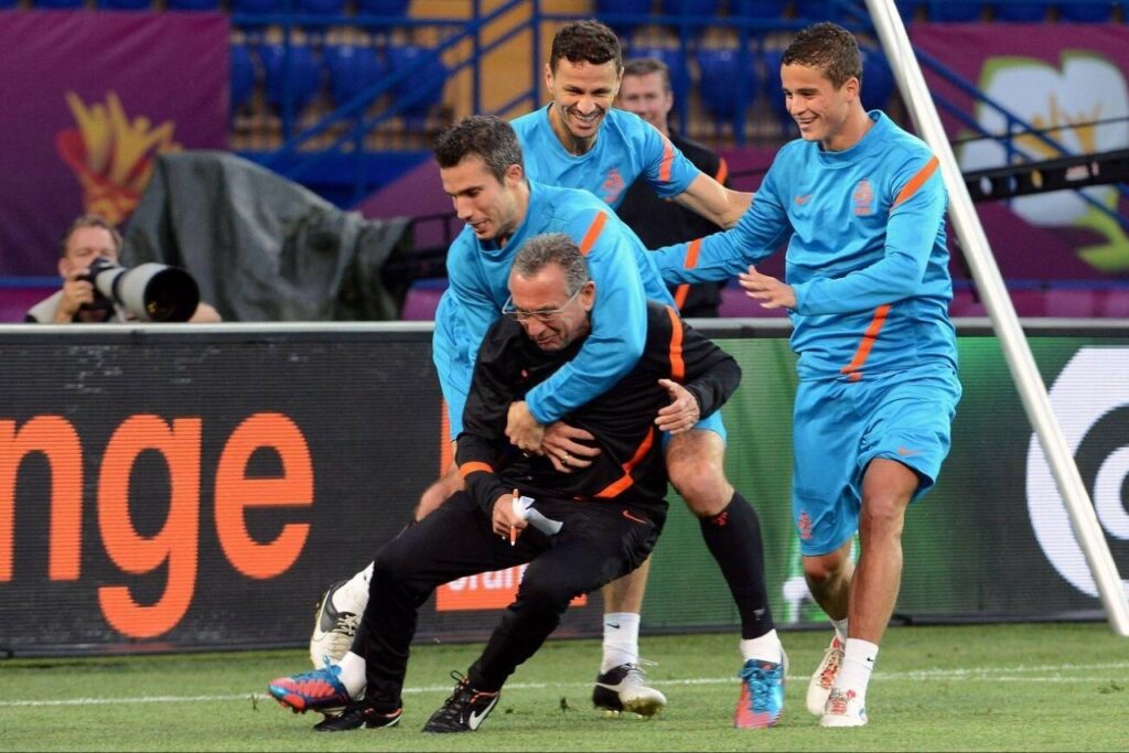 Van Persie and his Dutch teammate playing with the assistant coach during a training session in Krakow, Poland.
