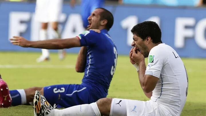Luis Suárez and Giorgio Chiellini on the floor, holding his teeth and shoulder respectively at the 2014 World Cup