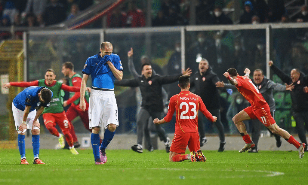 Giorgio Chiellini looks dejected as North Macedonia players celebrate in the background