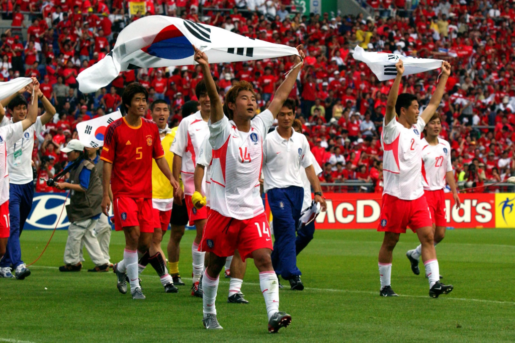 South Korean players carry flags in celebration of qualification to the semifinal
