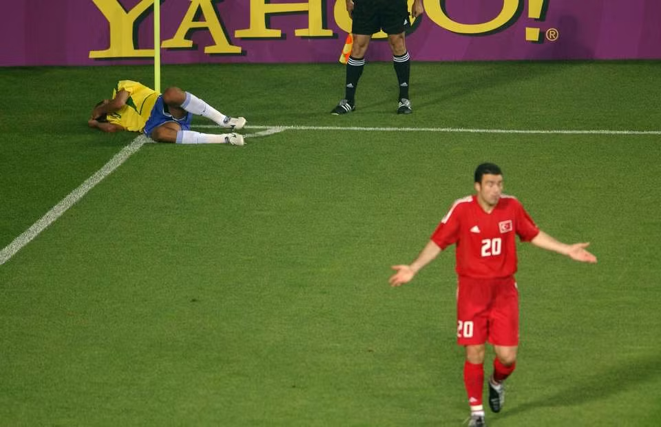 Rivaldo down on the ground near the corner flag, holding his face as Hakan Ünsal shrugs off