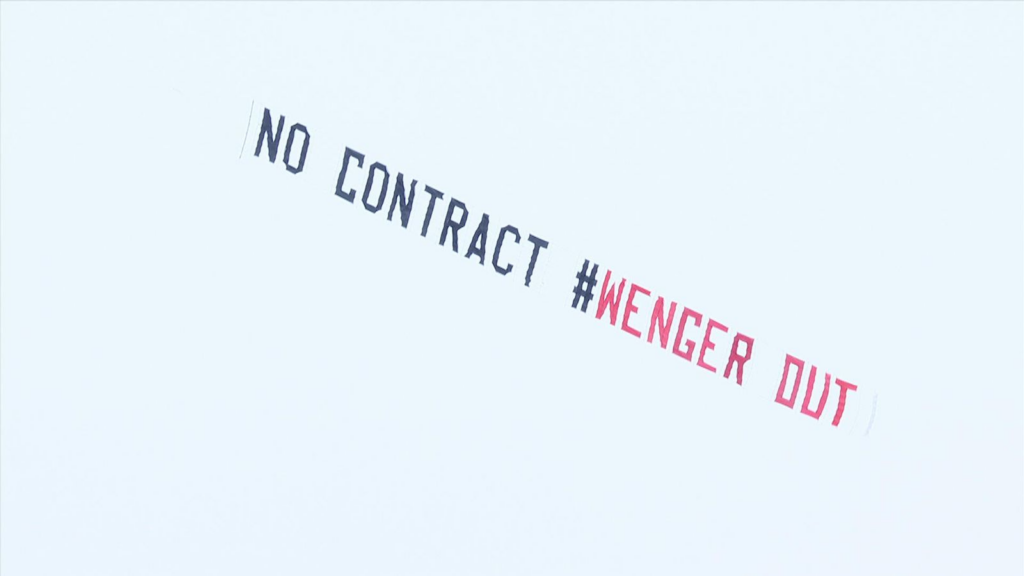 A plane flies over the Emirates Stadium with a banner saying 'No Contract #Wenger Out"