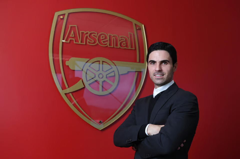 Mikel Arteta poses in front of the club logo during his unveiling as Arsenal manager.